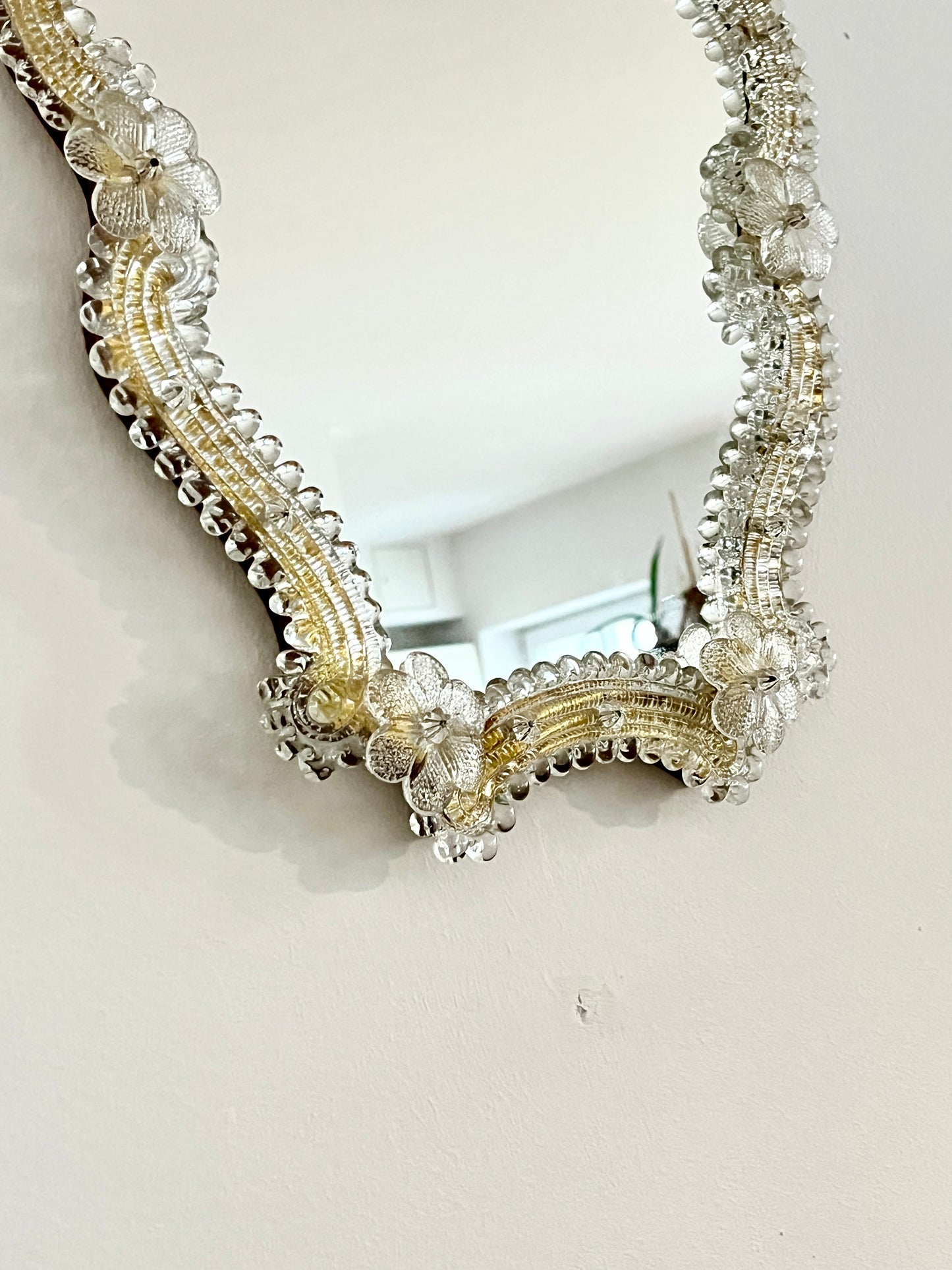 Decorative mirror with gold frame and floral details on a white background

