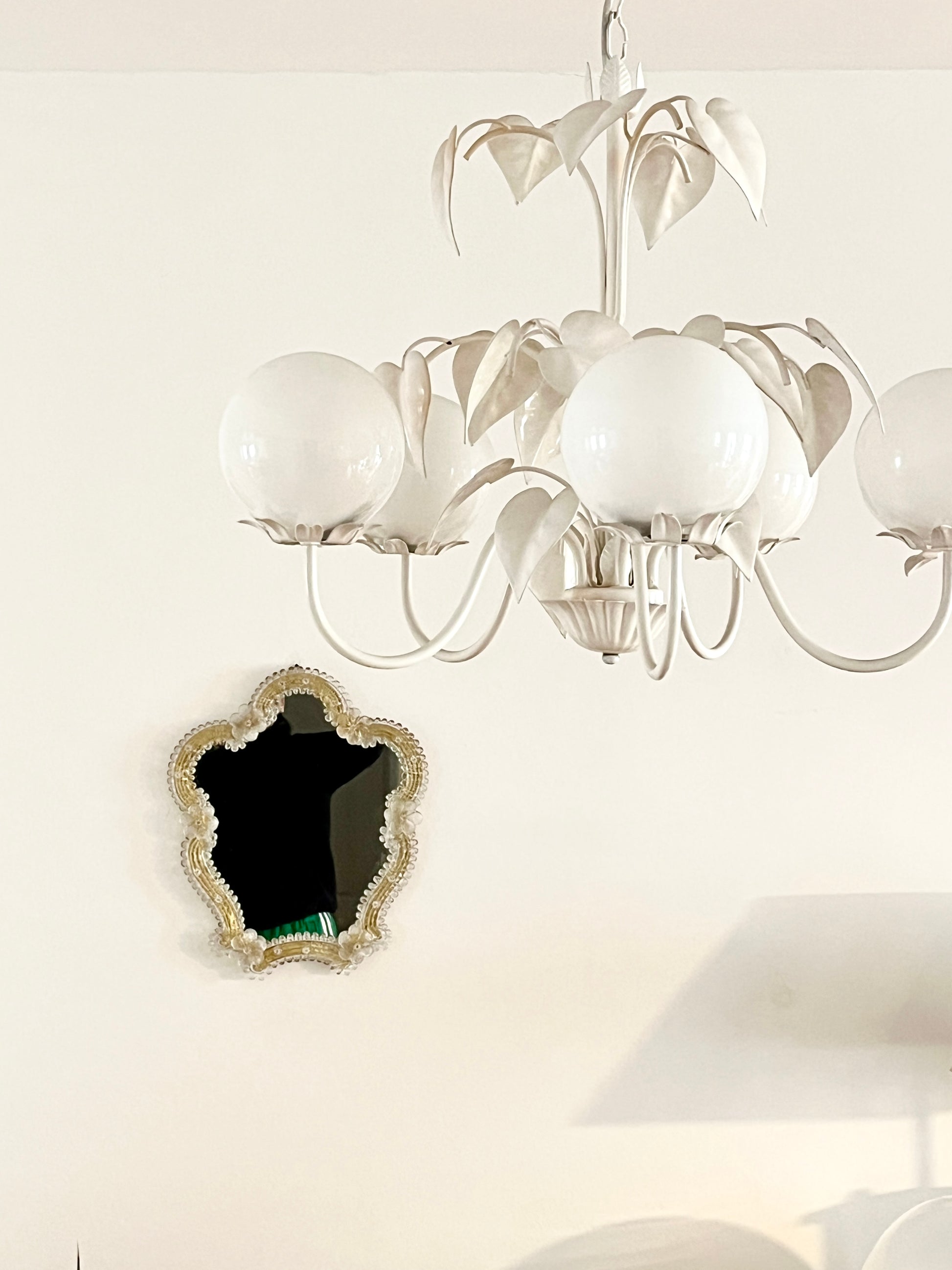 Decorative mirror with gold frame and floral details on a white background

