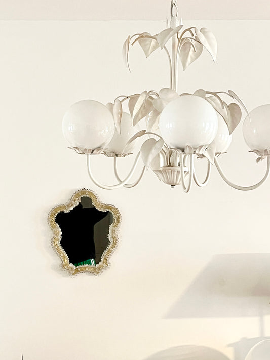 Decorative mirror with gold frame and floral details on a white background

