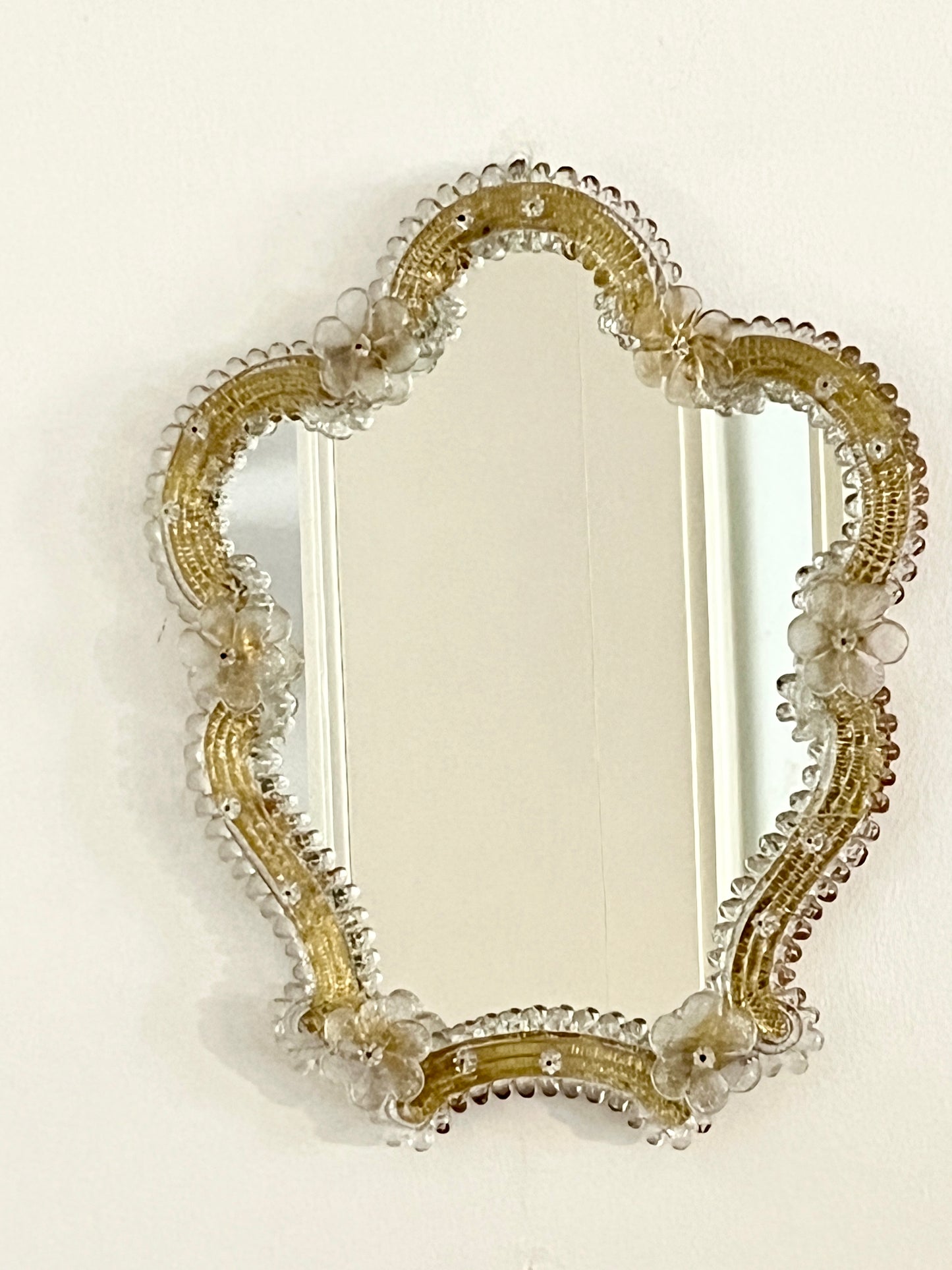 Decorative mirror with gold frame and floral details on a white background

