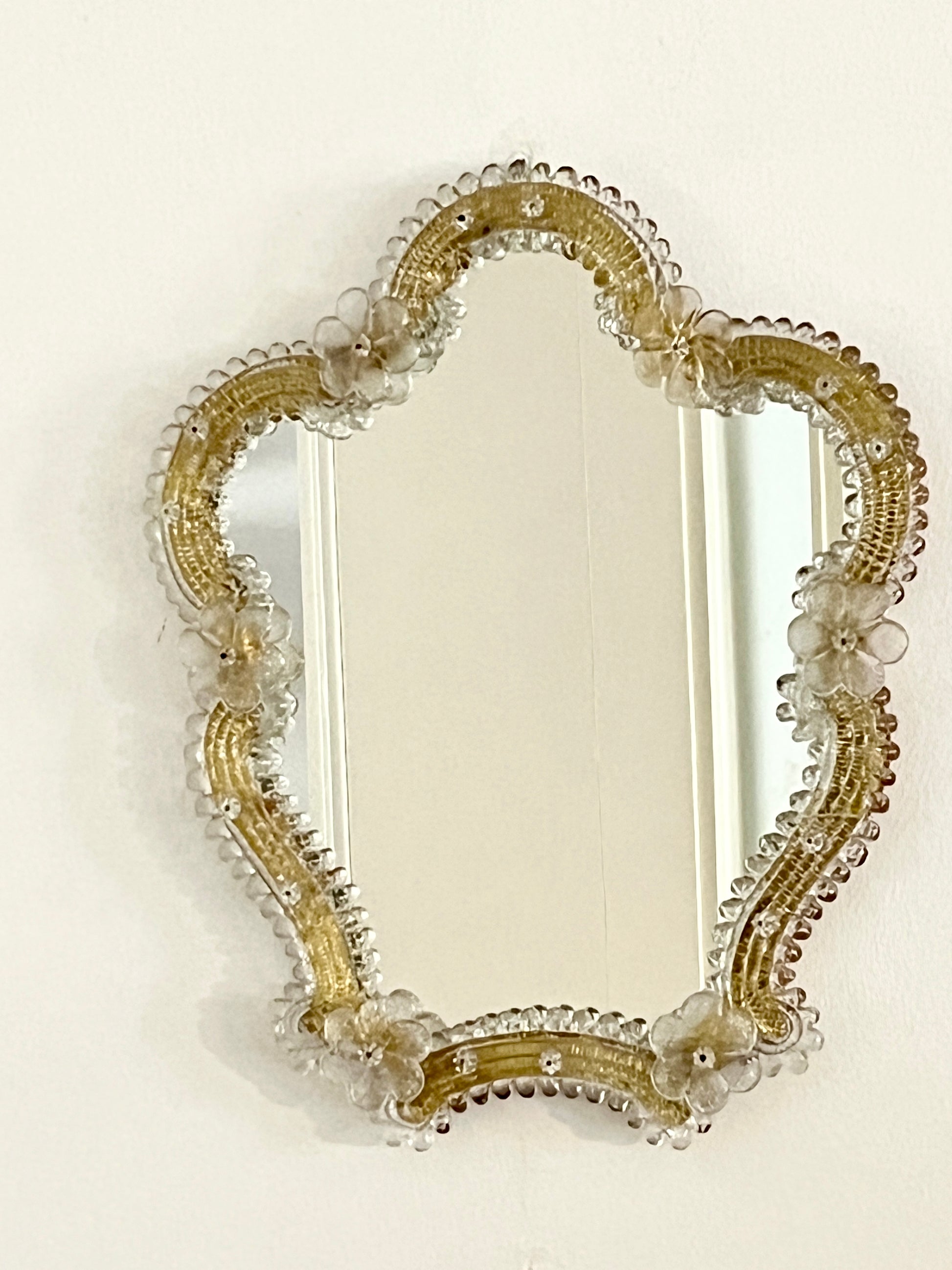 Decorative mirror with gold frame and floral details on a white background

